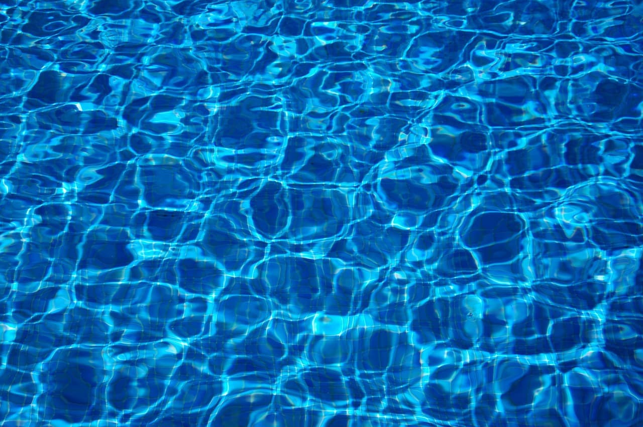 Caustic light patterns moving across the floor of a blue pool